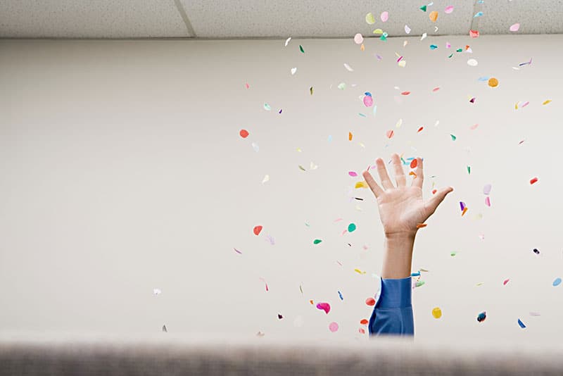 business worker throwing confetti into the air in cubicle.